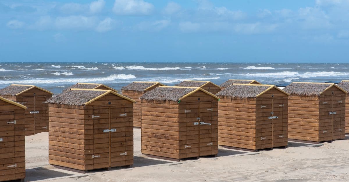 Rustieke strandhuisjes op rij langs de zandstranden, ideaal voor camping Zuid-Frankrijk liefhebbers.