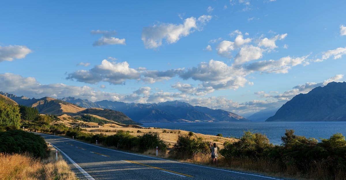 Scenic mountain road winding past glacial lakes on a New Zealand road trip for US travelers.