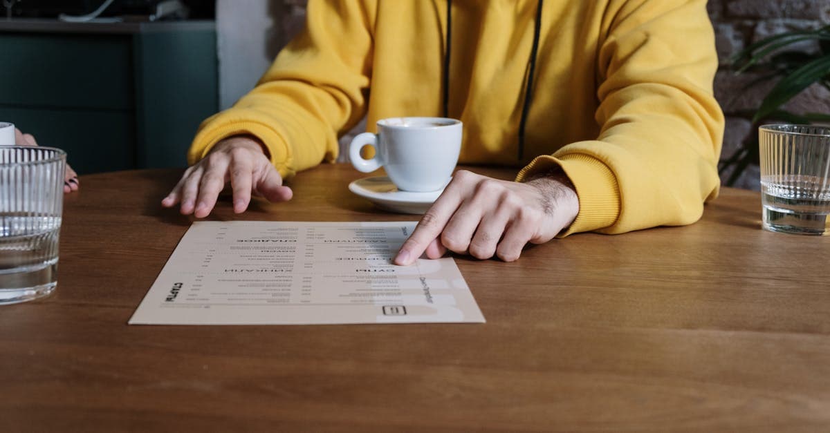Traveller in yellow hoodie pointing at a menu to decide what to eat in Bali warung