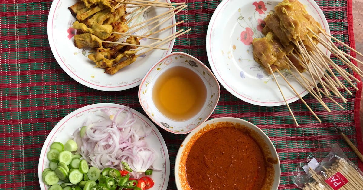 Brochetas de satay de pollo con salsas picantes y verduras frescas en un mercado tailandés