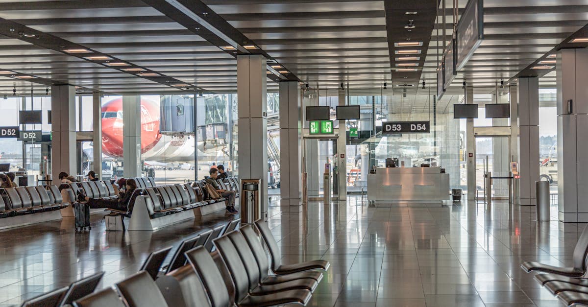 Rolig lufthavnsterminal med tomme sæder og fly synlige gennem store glasvinduer