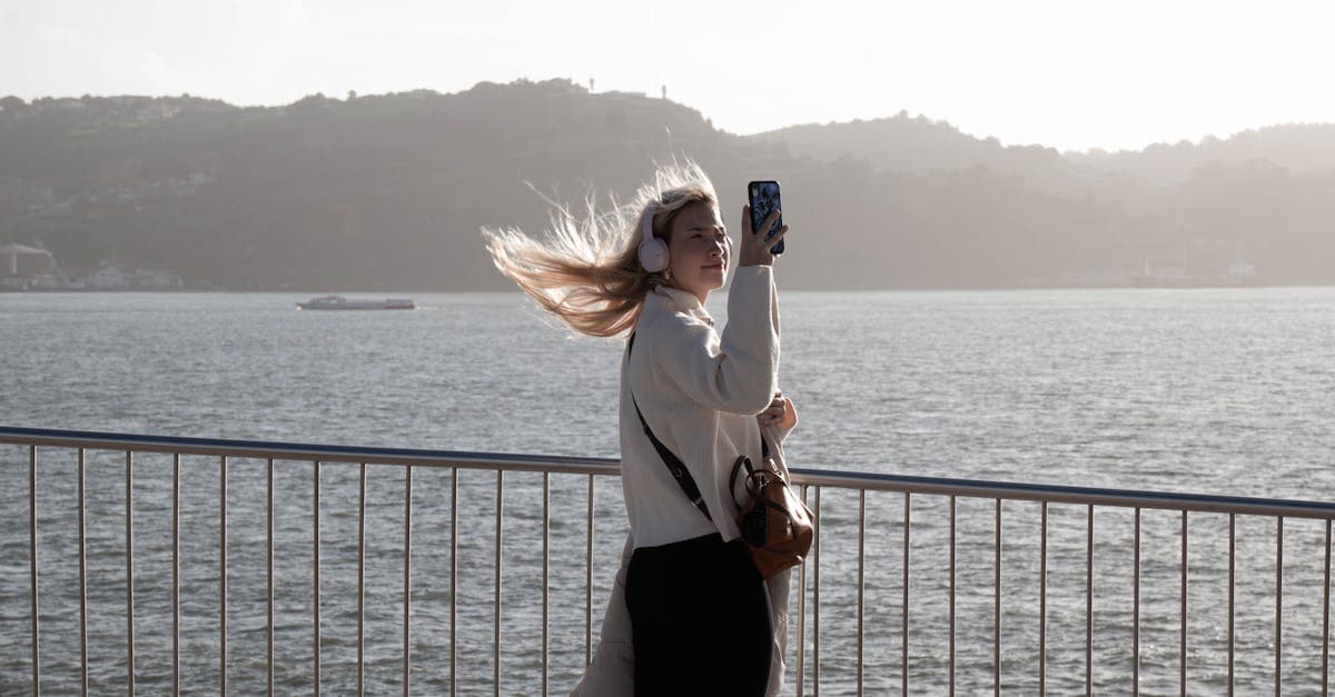 Viajante com auscultadores a tirar selfie junto à frente ribeirinha, ligada enquanto explora o Algarve