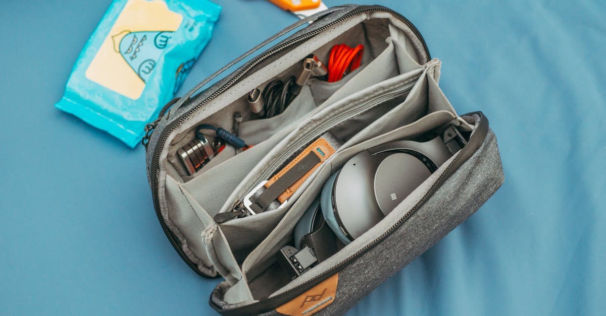 Top-down view of organized travel tech bag containing headphones, charging cables, and cleaning wipes