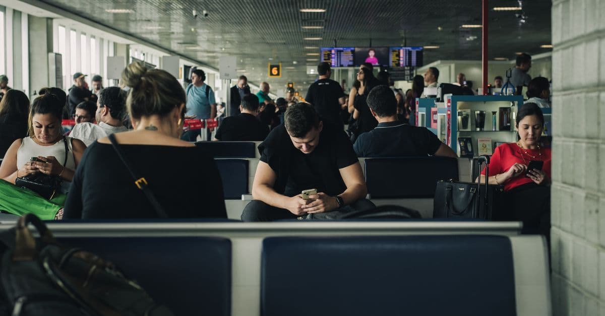 Reisende nutzen ihre Smartphones am Rhodos Flughafen, um WLAN und mobile Internetoptionen zu testen