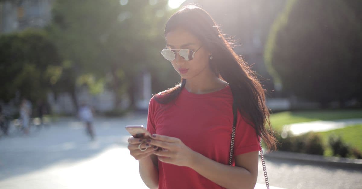 Kobieta wysyła wiadomości tekstowe na zewnątrz, sprawdzając działanie t mobile roaming za granicą
