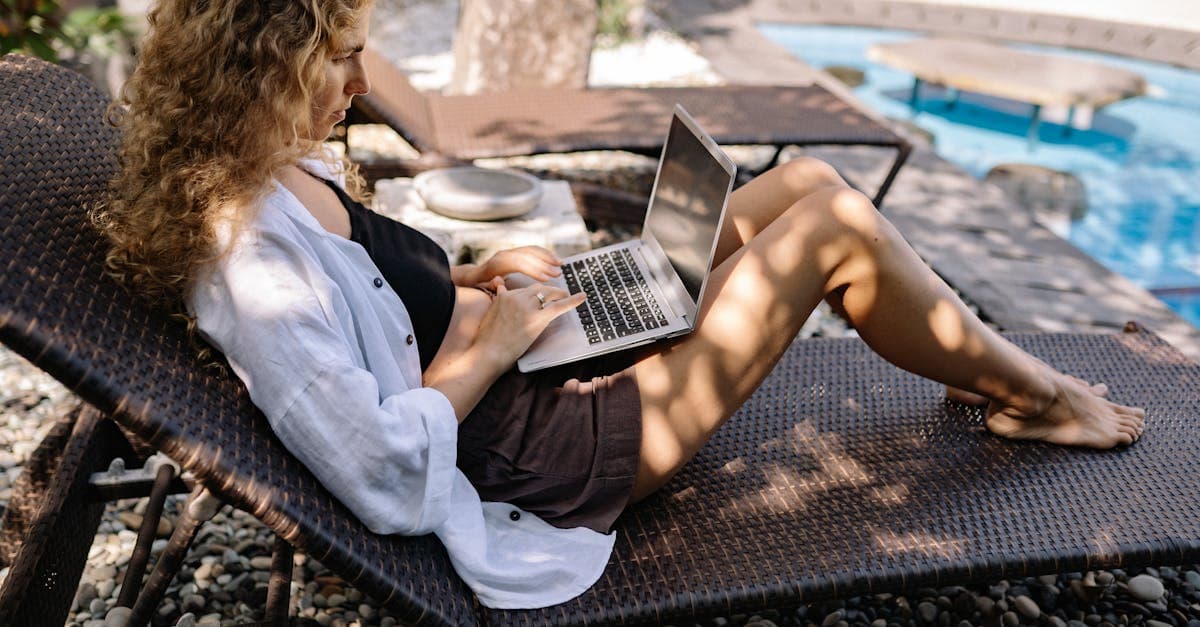 Mujer de cabello rizado trabajando en laptop junto a alberca, representando la libertad financiera del working link.