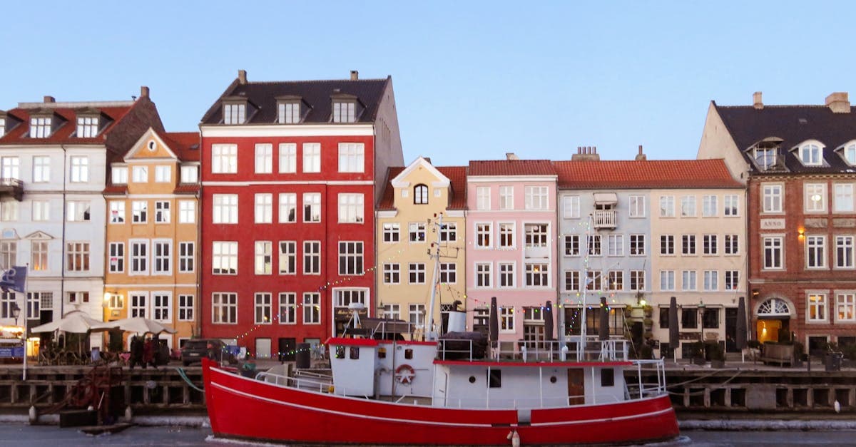 Nyhavn i solskin med rød båd og farverige bygninger – ideel årstid for free walking tour Copenhagen