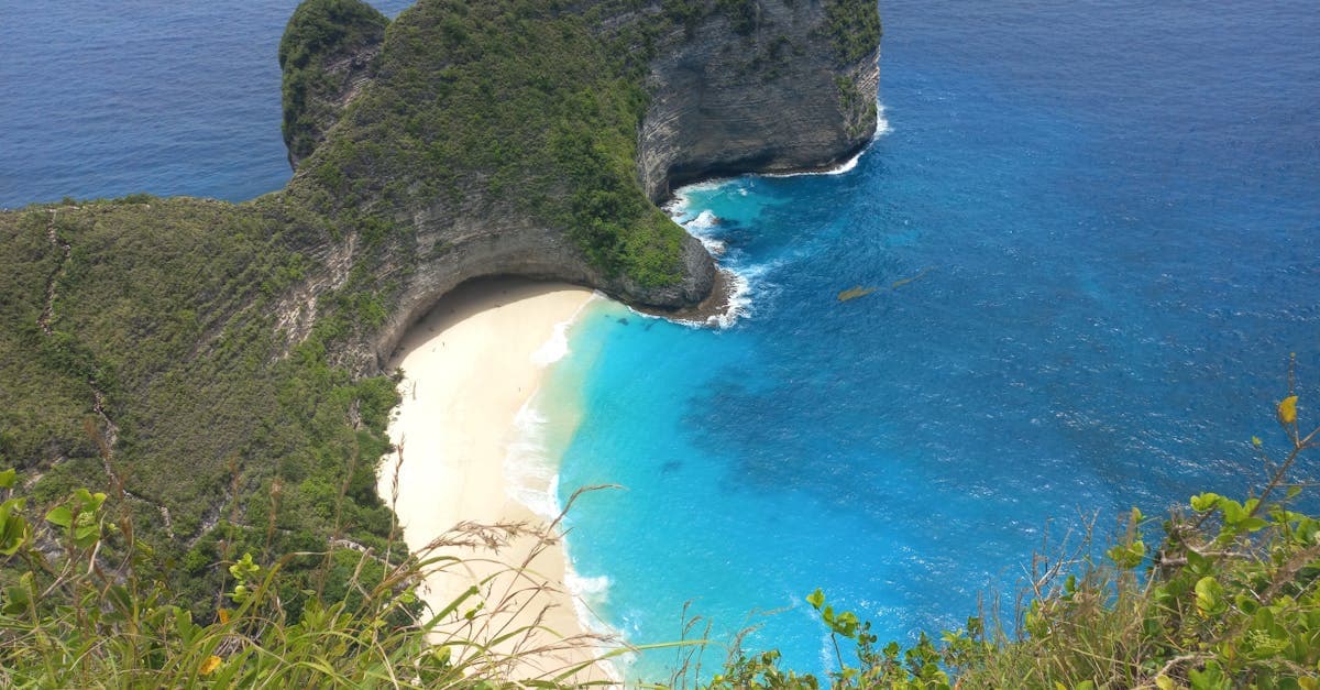 Bali vejr på Nusa Penida: turkisblåt vand og hvid sandstrand ved Kelingking Beach set fra luften