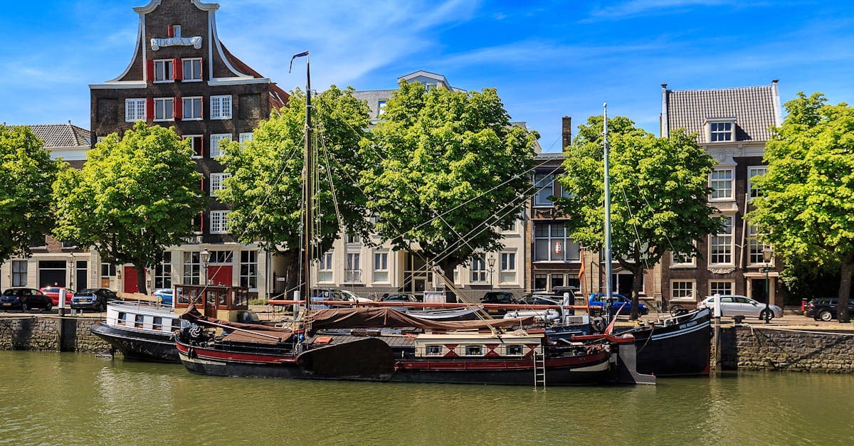 Historische schepen langs de gracht van Dordrecht omgeven door klassieke Nederlandse architectuur als reisbestemming.