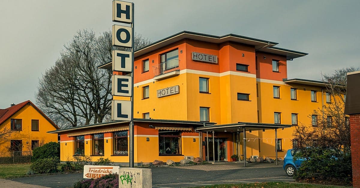Vibrant yellow hotel exterior with signage under cloudy autumn sky.