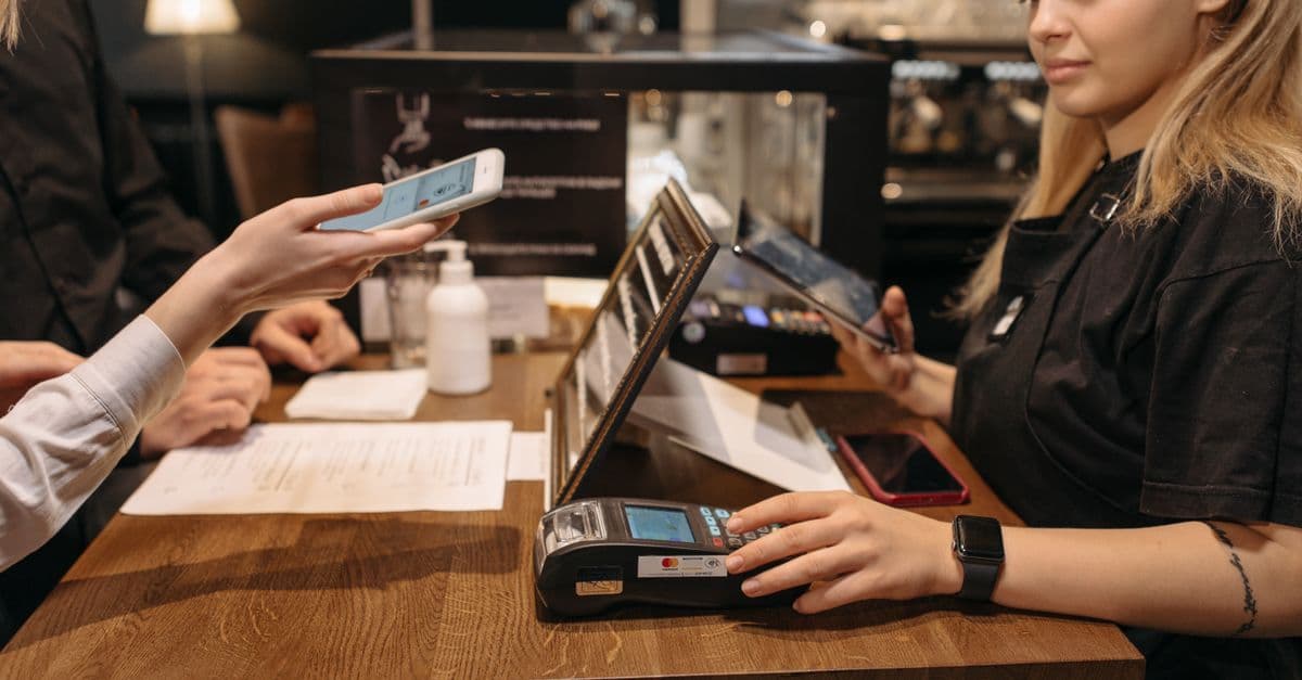 Cliente che effettua un pagamento contactless con iPhone, a confronto tra assistenza indipendente e autorizzata Apple