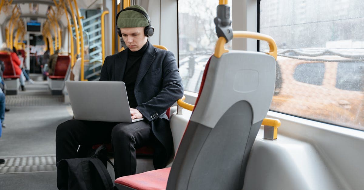 Mężczyzna pracujący na laptopie w tramwaju – work and travel łączy pracę z podróżowaniem
