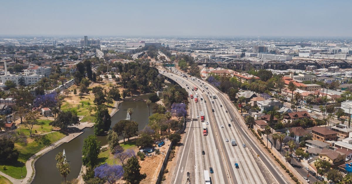 Bustling Los Angeles freeway beside a lush urban park, key route for Canadian travellers planning a 2028 Olympics trip.