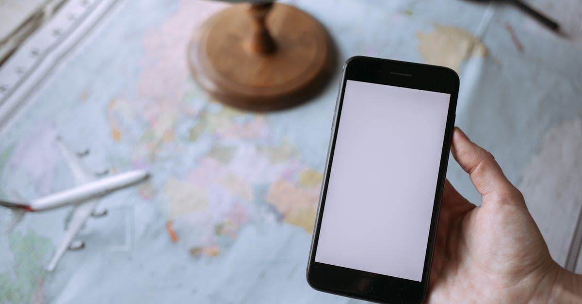 Hand holding a smartphone over a world map to stay connected while travelling in India.