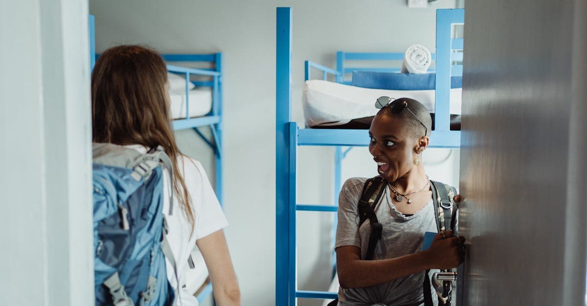 Two women with backpacks arriving at a bright hostel dormitory, proving solo female travel can be safe