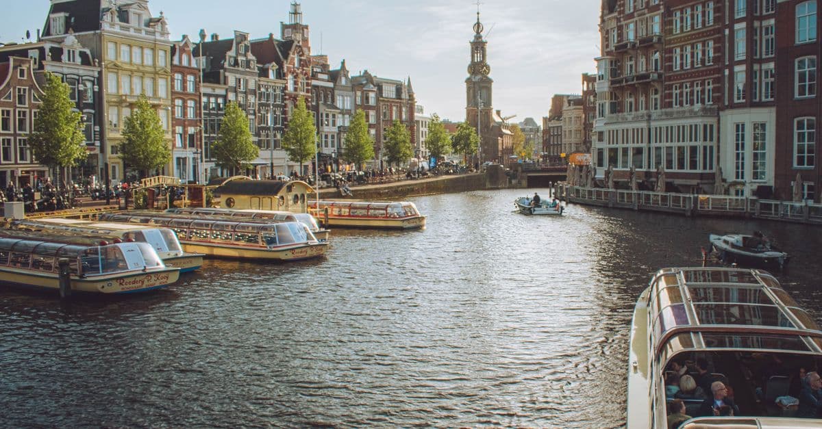 Canal boats gliding past centuries-old Amsterdam buildings, ideal for exploring amsterdam holidays on the water.