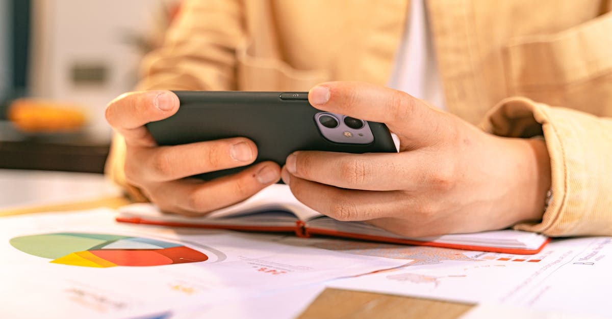 Business professional checking a smartphone beside financial charts, comparing Tesco SIM and 02 sim only deals
