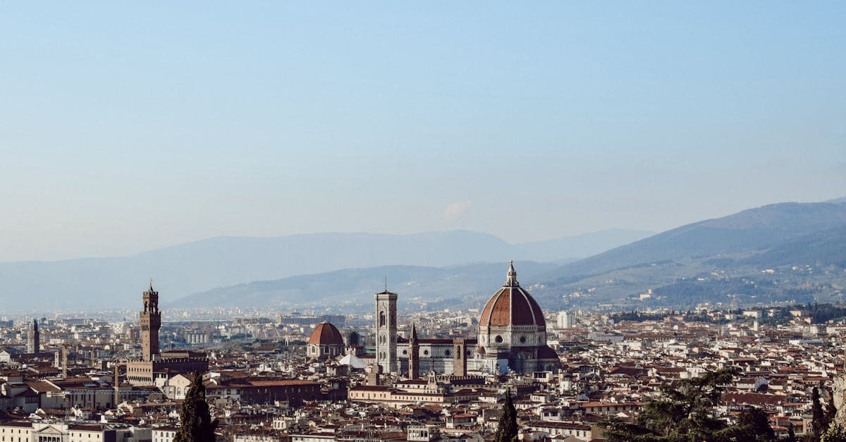 Borgo storico europeo con case antiche, chiesa e montagne sullo sfondo, ideale per un weekend economico