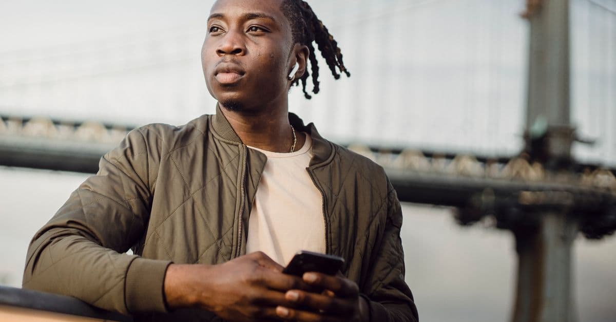 Young traveler using a smartphone to activate a travel eSIM while listening to music outdoors