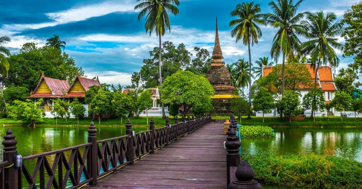 Starożytna świątynia w Sukhothai otoczona wodą i zielenią – wskazówka kiedy lecieć do Tajlandii.