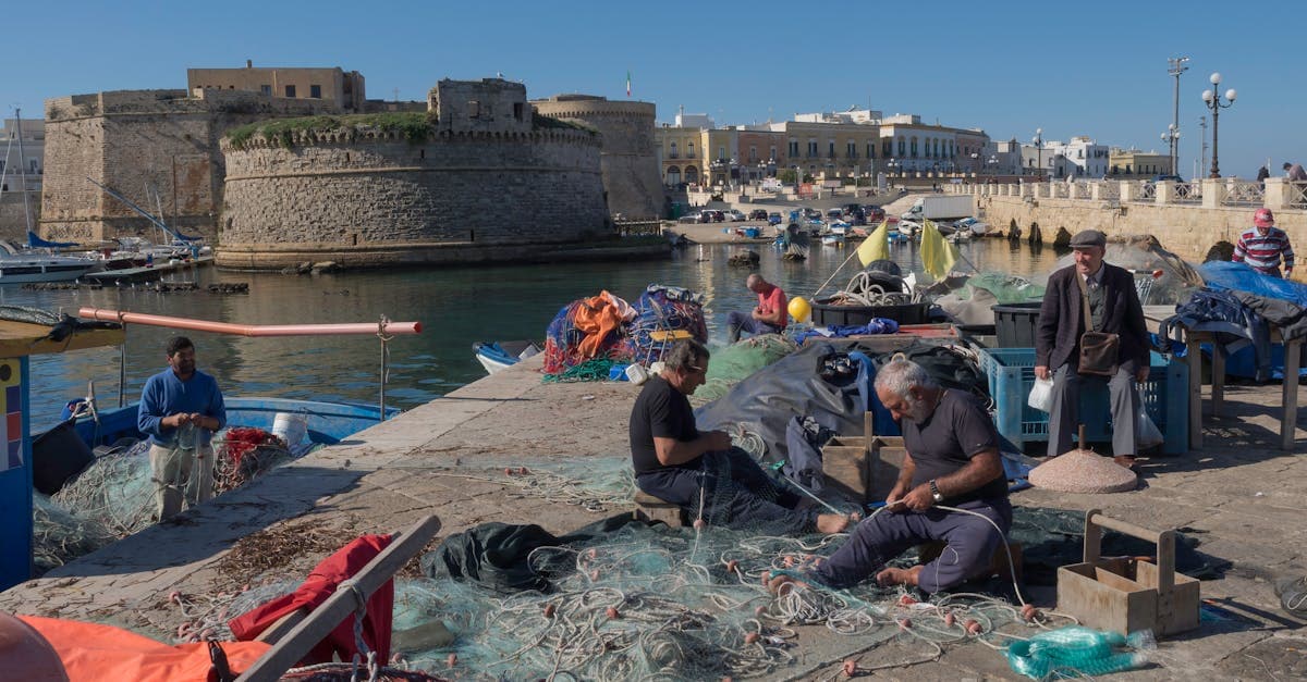 Pescatori che riparano reti al castello medievale di Gallipoli, immagine evocativa delle possibilità di lavorare all'estero