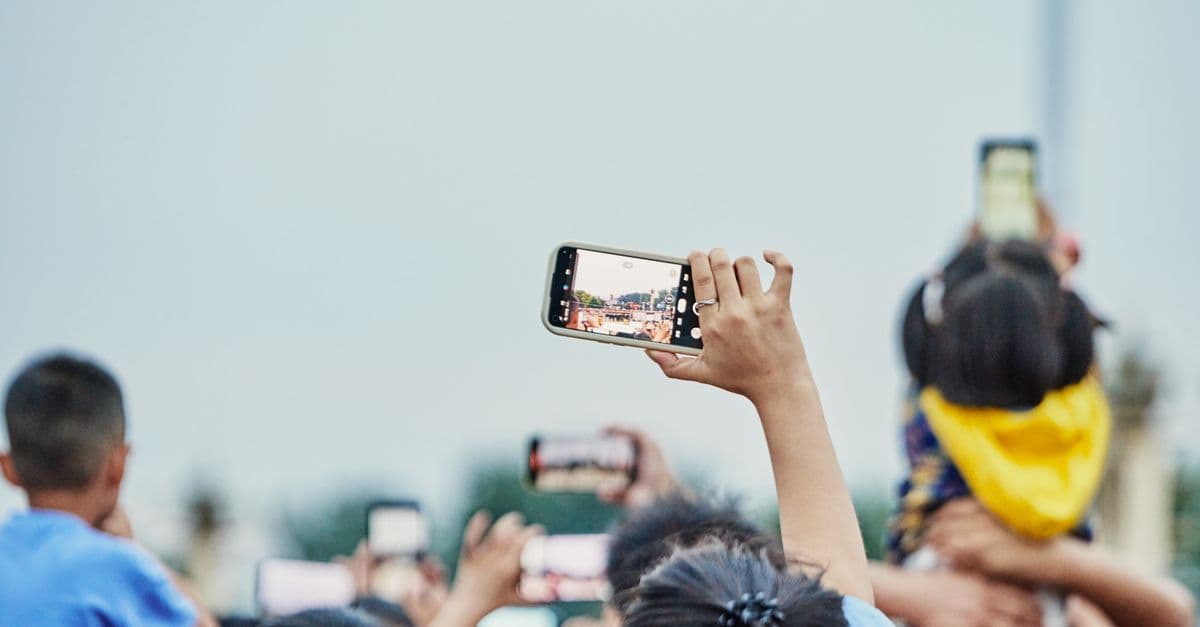 神宮球場でスマートフォンを掲げて試合を撮影するファンたち、旅行者向けeSIMで快適な通信環境を確保する様子