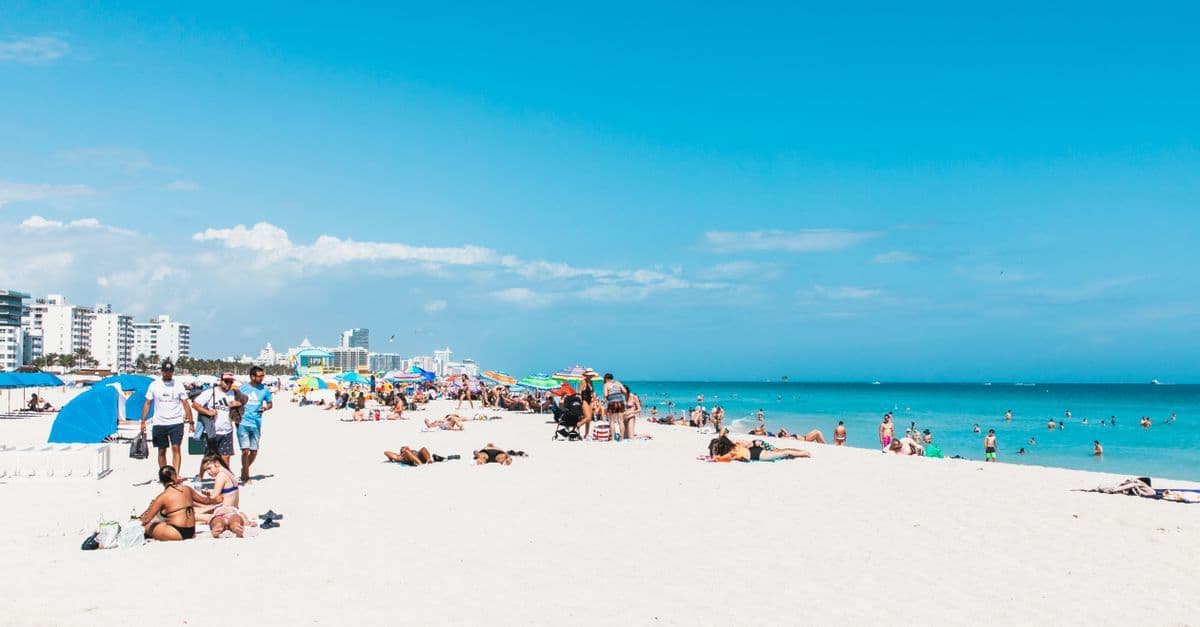 Sunbathers and colourful umbrellas line Miami Beach during classic Florida weather.