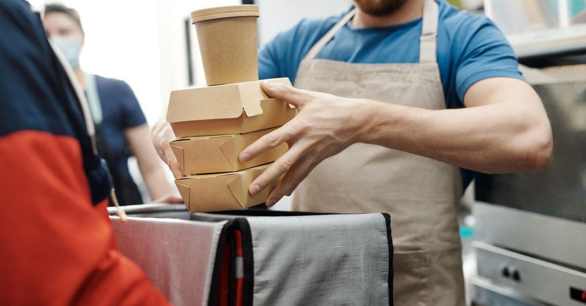 Lieferfahrer übergibt Essenspakete in einer Küche – food meal delivery in Deutschland.