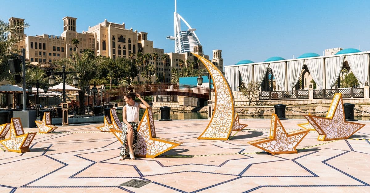 Vrouw ontspant bij een kunstinstallatie met het iconische Burj Al Arab op de achtergrond in Dubai.