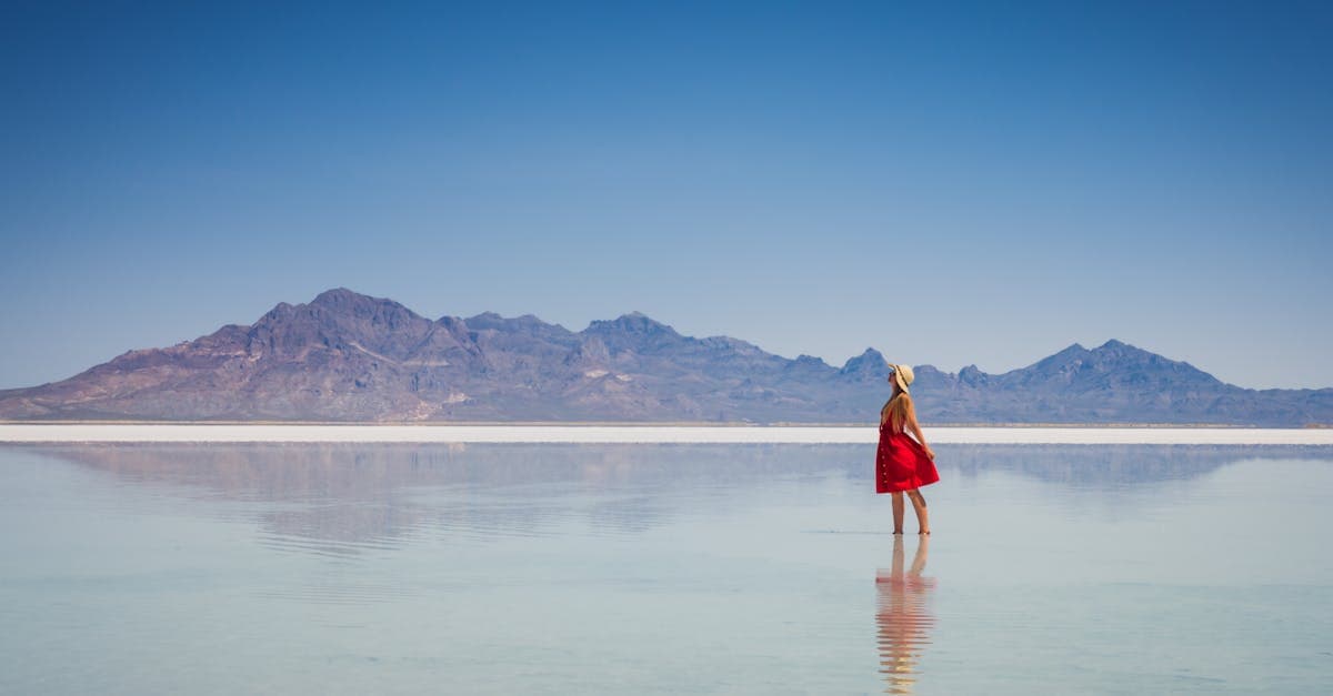 Woman in a red dress standing on the Bonneville Salt Flats, confidently traveling alone without awkwardness.