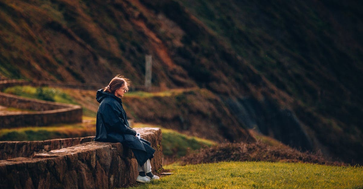Mujer disfrutando de las vistas de Bilbao desde un muro de piedra, gestionando el presupuesto de su viaje solo.