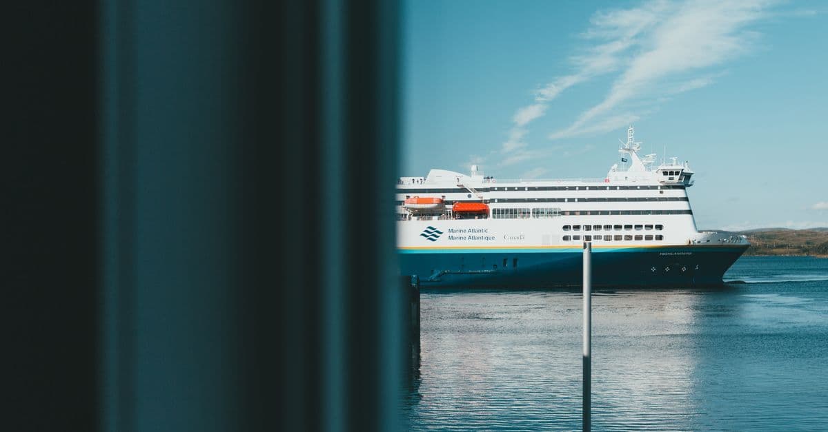 Ferry sailing on a clear ocean under blue skies, captured from a calm waterfront.