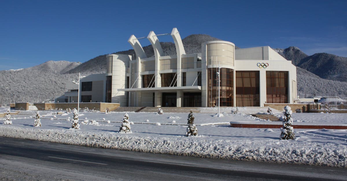 Stade olympique à l'architecture moderne entouré de montagnes enneigées, site des disciplines du programme JO 2026