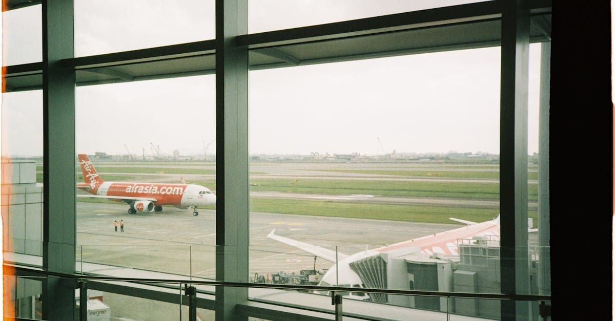 เครื่องบิน AirAsia แล่นบนรันเวย์มองจากภายในอาคารผู้โดยสาร ก่อนเริ่มขั้นตอน airasia check in ผ่านแอปและเคาน์เตอร์