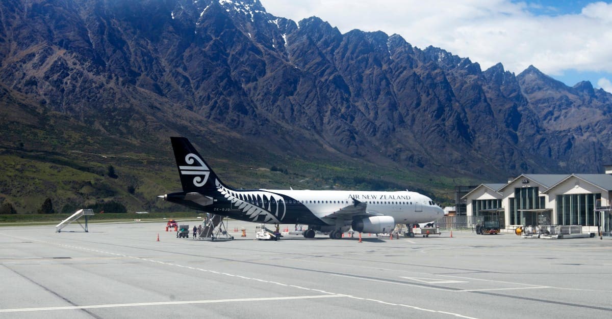 Air New Zealand plane at Queenstown Airport with dramatic Southern Alps mountain backdrop.![image