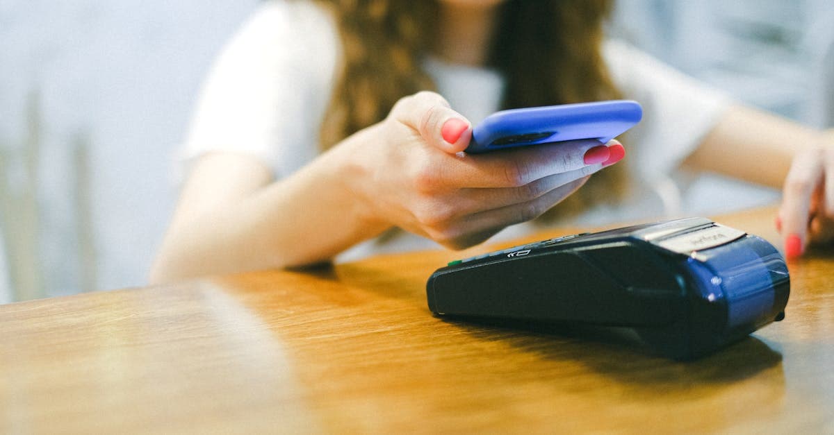 Woman using smartphone for contactless payment, illustrating how a Tesco pay as you go SIM keeps you connected.