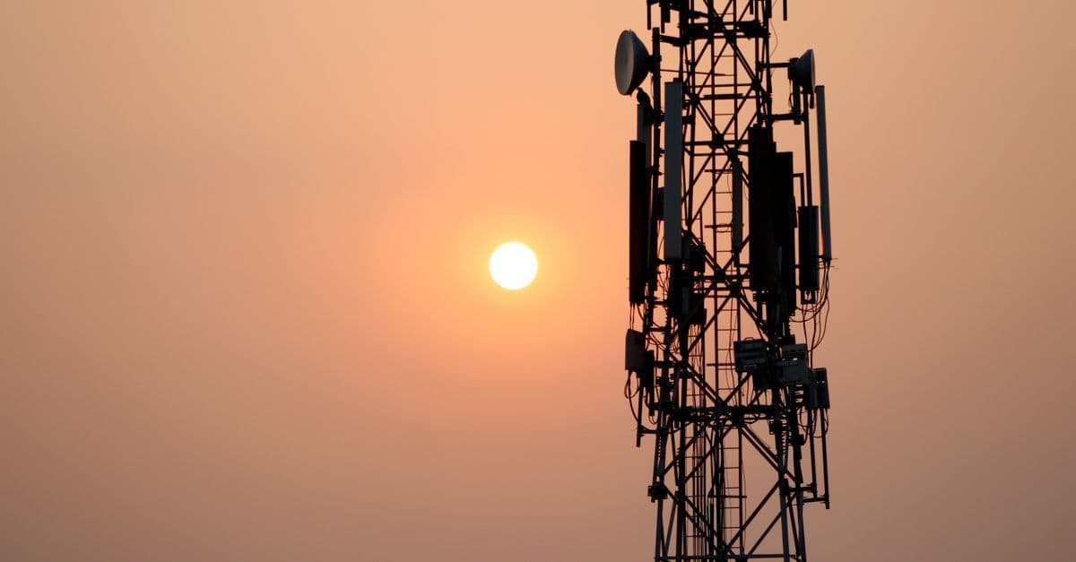 Communication tower silhouetted against a sunset sky, representing the UK network powering SMARTY SIM coverage.