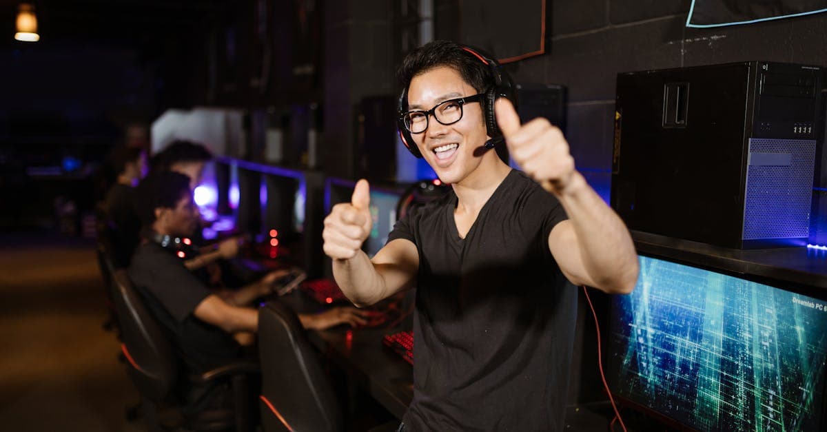 Happy gamer giving a thumbs up at a UK internet cafe with rows of gaming computers.