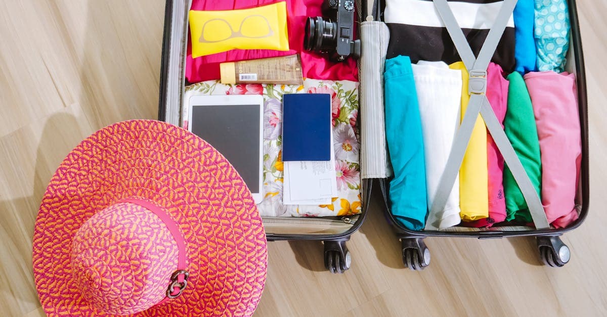 Open suitcase neatly packed with clothes, a sun hat, and a camera, illustrating the 5-4-3-2-1 packing rule.