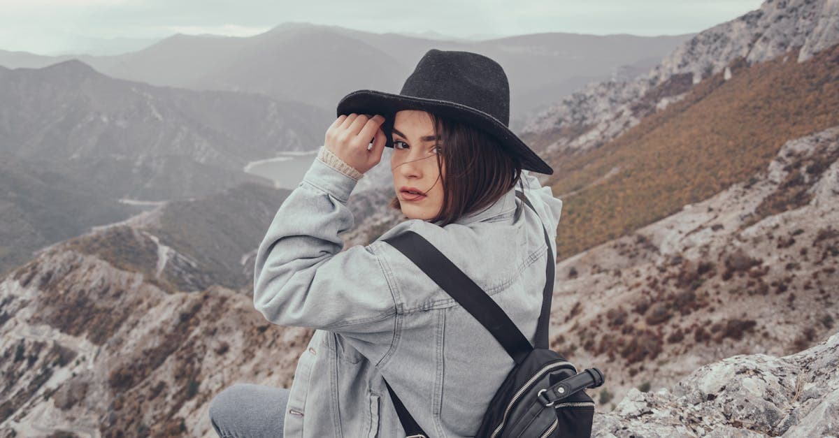 Perempuan muda berpose di puncak gunung menikmati pemandangan, solo trip aman dan menyenangkan.