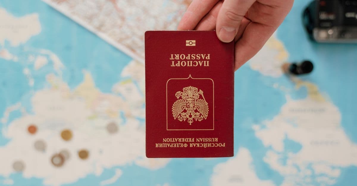 Mano sosteniendo pasaporte sobre mapa con los documentos necesarios para tramitar el working holiday visa