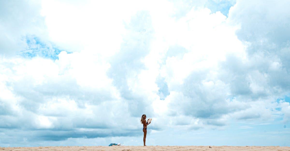 Podróżniczka z telefonem na plaży planuje kiedy lecieć do tajlandii na wymarzony urlop.