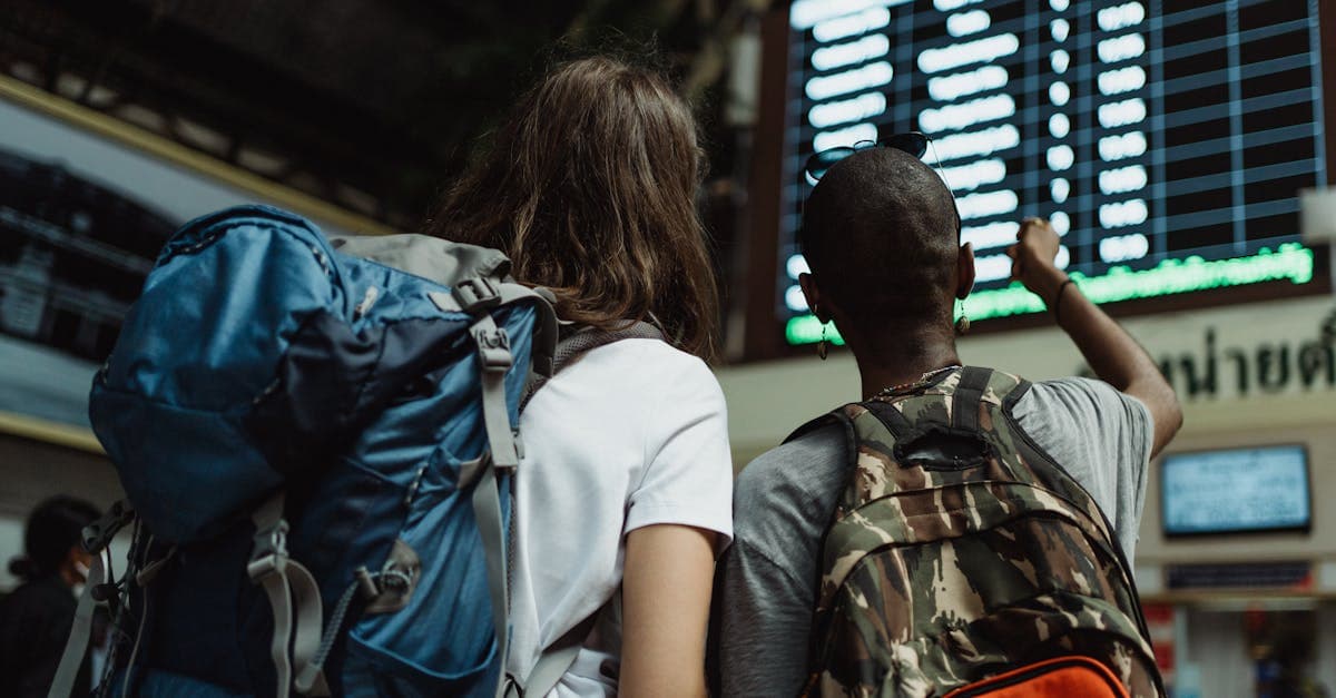 Two travellers checking train departure boards, ready to activate a travel eSIM before boarding their flight.