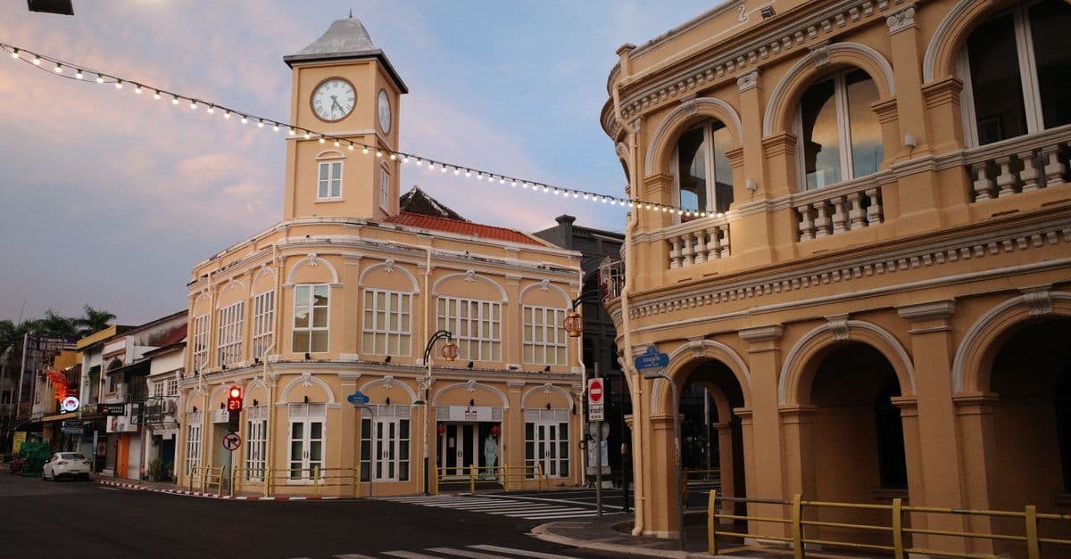 Pastel Sino-Portuguese buildings and a clock tower line a street in Phuket Old Town.