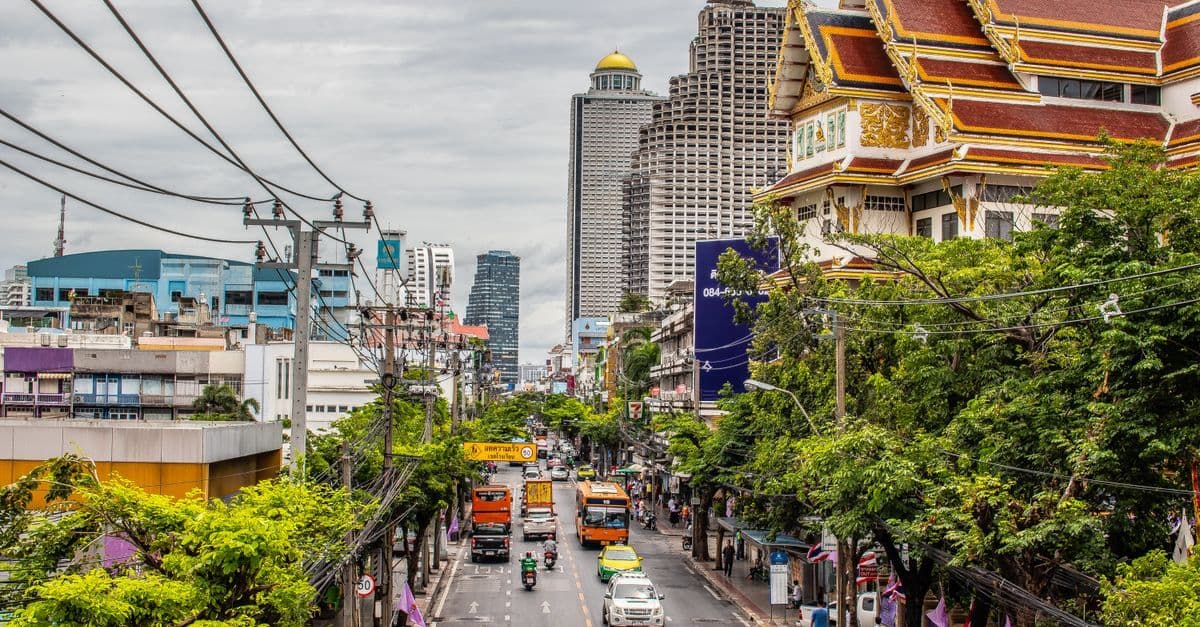 Livlig gatumiljö i Bangkok med trafik och ikonisk arkitektur, perfekt för svenska resenärer med mobildata.