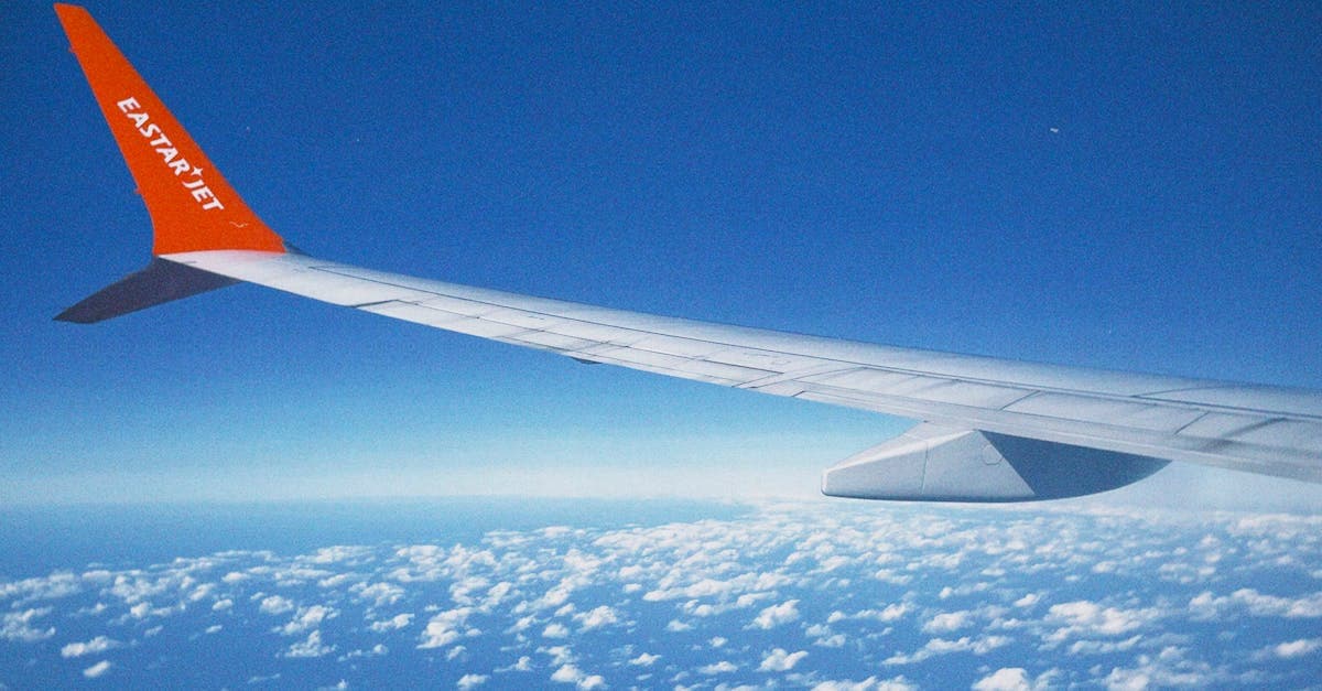Budget airline wing view over clouds on a short-haul flight departing Singapore Changi Airport.