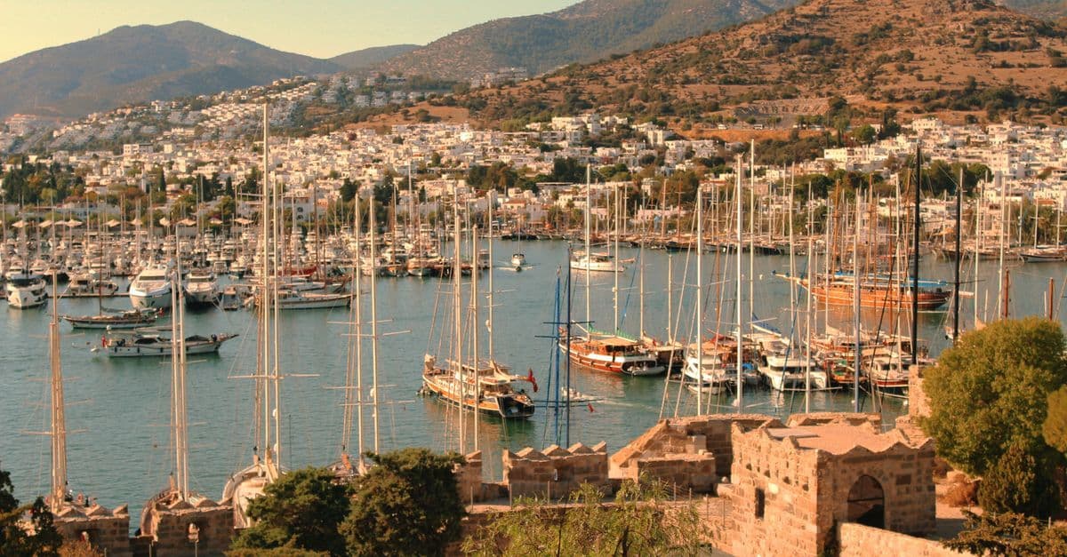 Sailboats fill the harbour in Bodrum, Turkey, beneath white hillside houses and mountains.