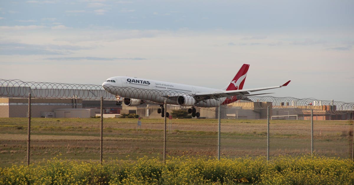 A Qantas airplane landing on a runway at Melbourne Airport during the day.