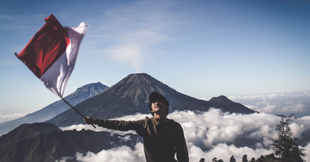 Pendaki mengibarkan bendera Indonesia di puncak gunung, merayakan kebebasan perjalanan negara bebas visa