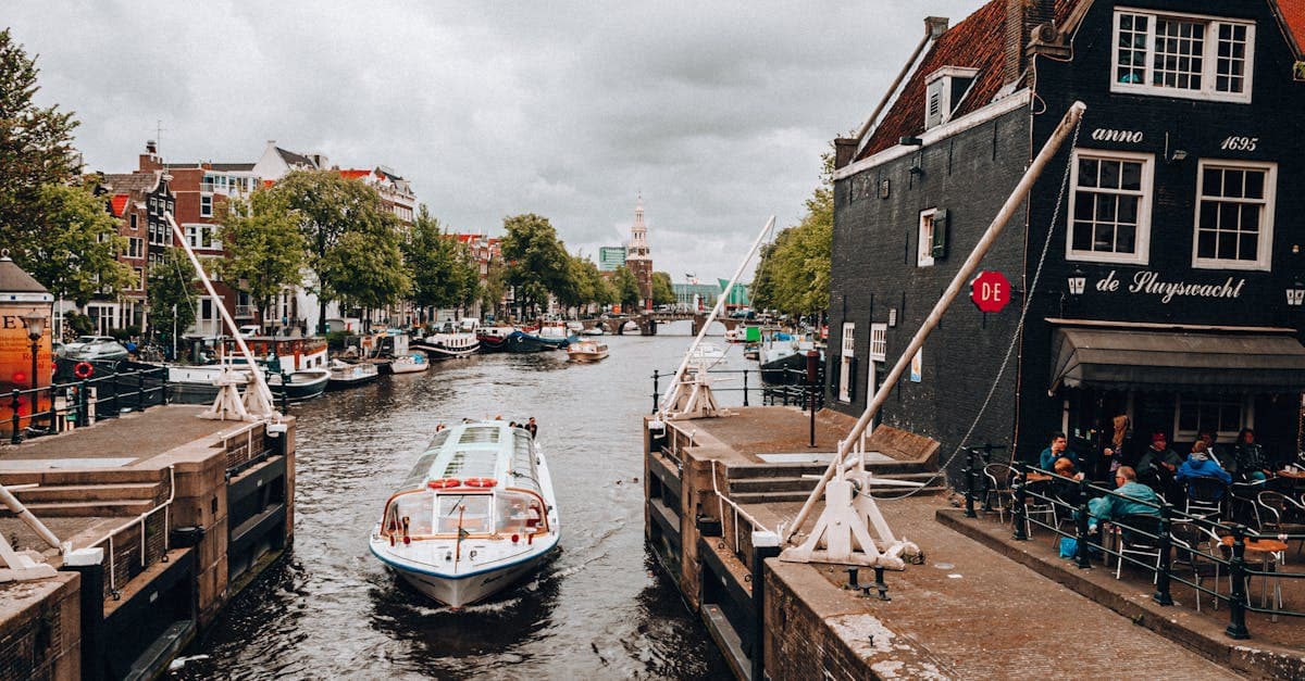 Charmante Amsterdamse gracht met rondvaartboot en historische gevels, ideaal voor reizigers die een prepaid sim card netherlands zoeken